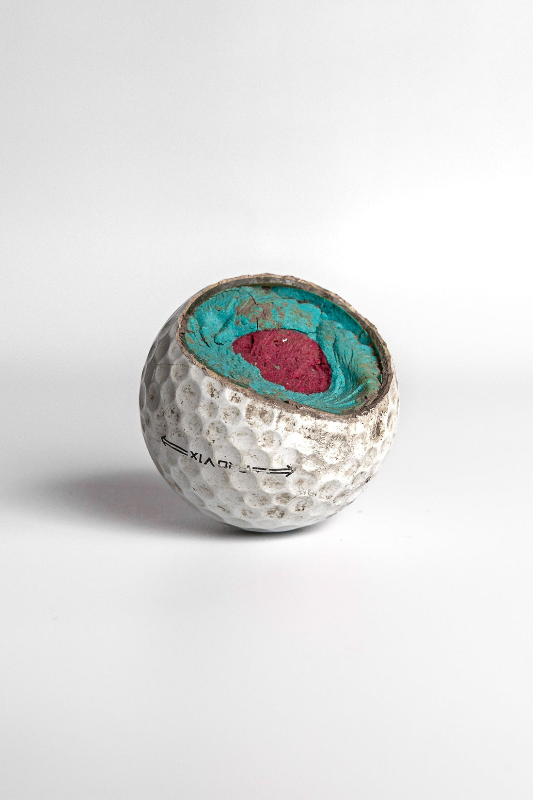 Titleist Pro V1 cut open showing turquoise and pink interior core layers white background