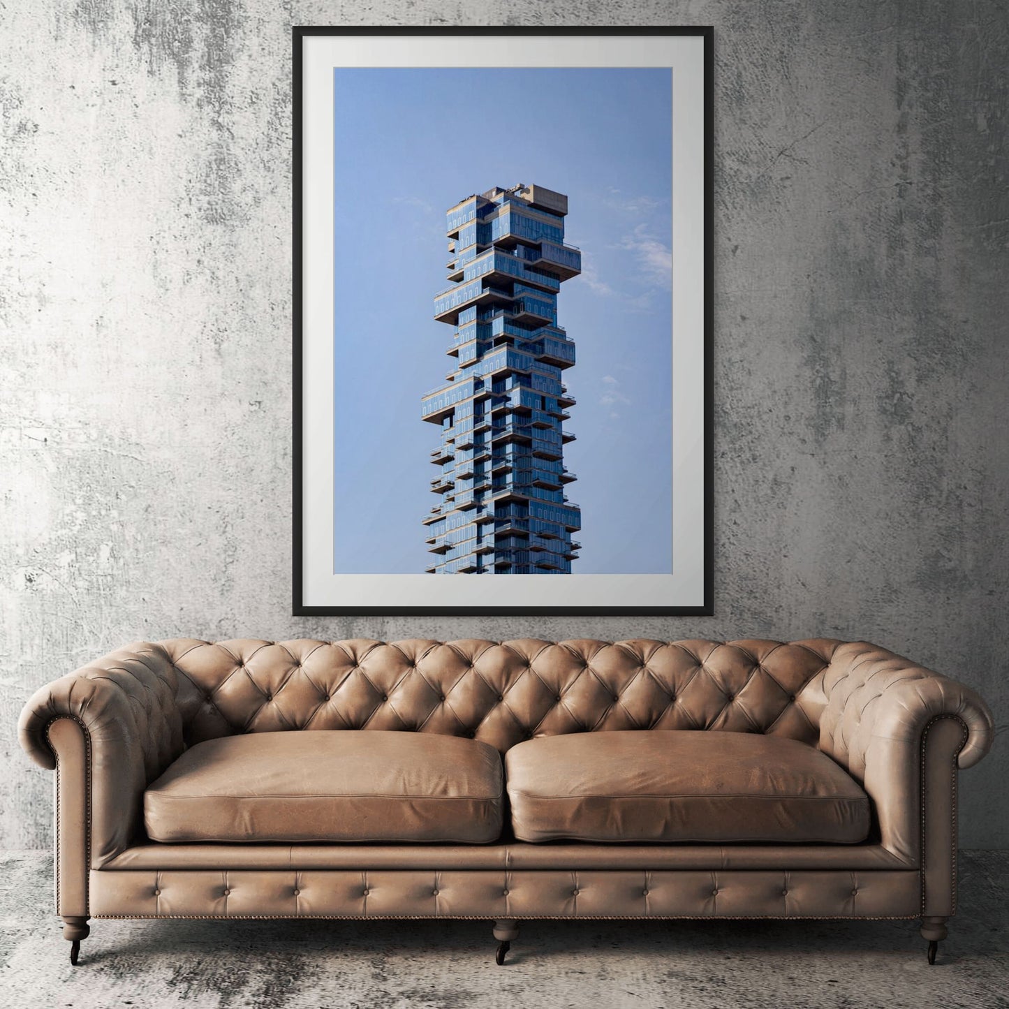 Manhattan architecture framed print displayed above tan leather sofa in living room