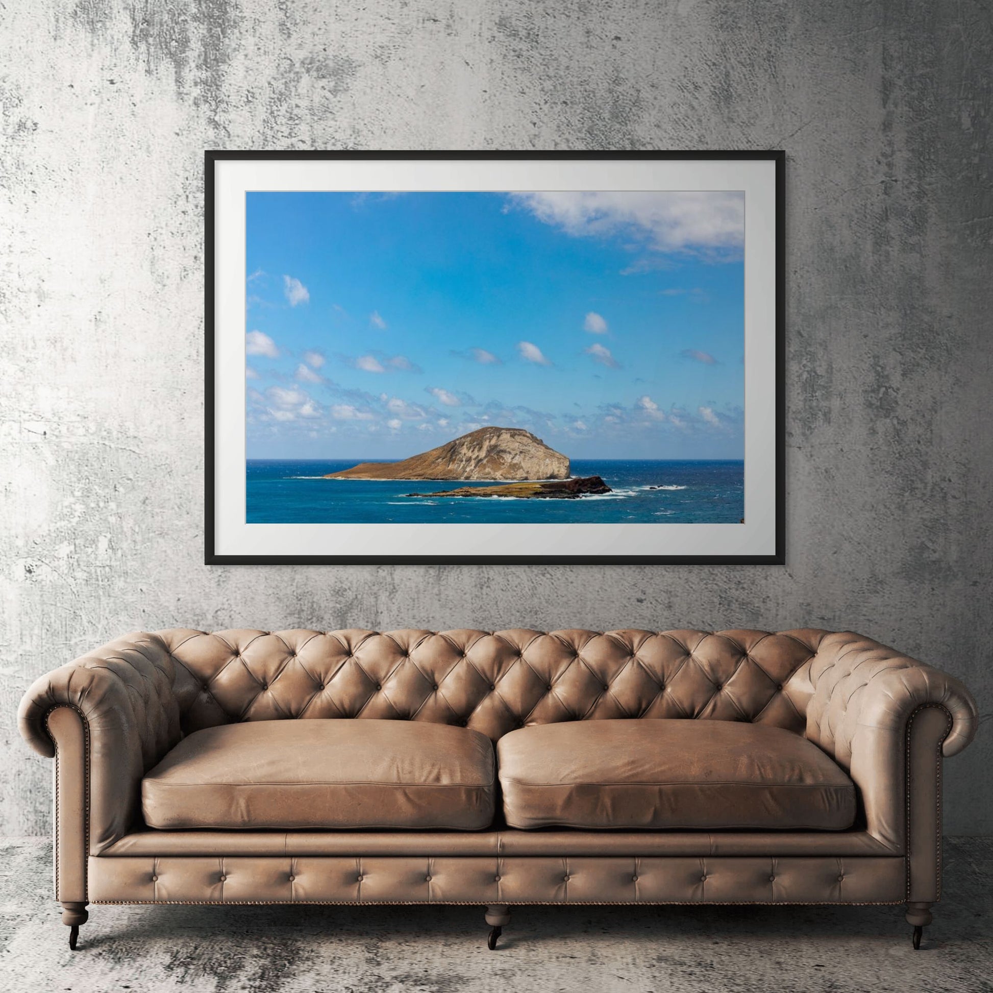 Oahu offshore island framed print displayed above tan leather sofa in living room