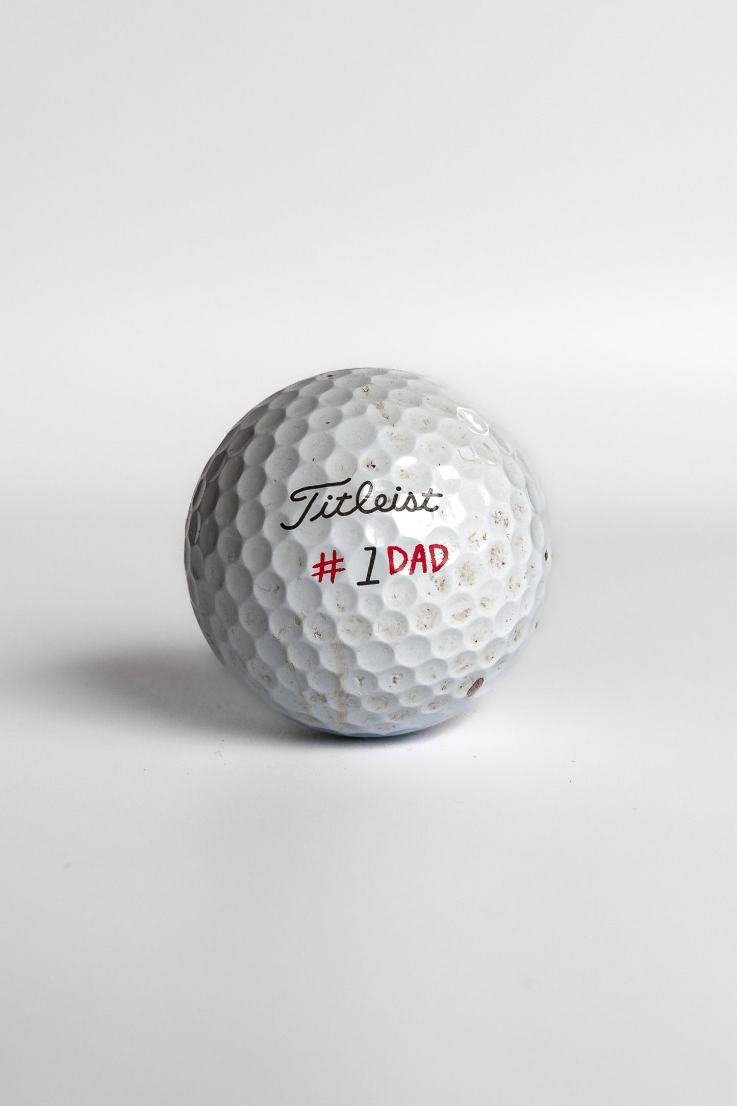 Titleist Pro V1 golf ball with #1 Dad red text white background