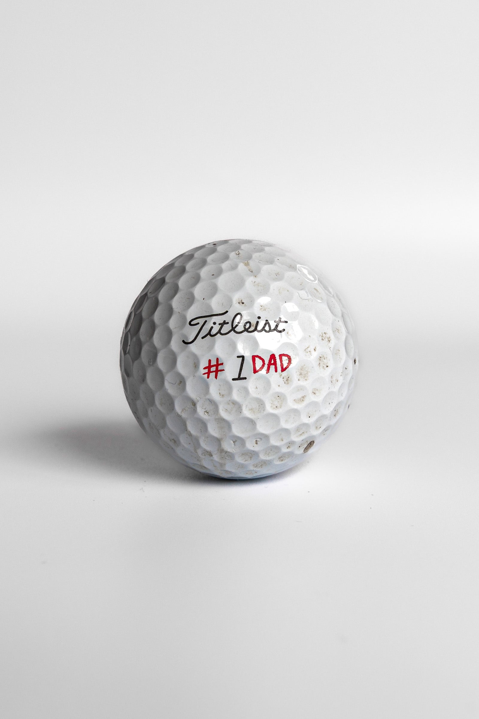 Titleist Pro V1 golf ball with #1 Dad red text white background