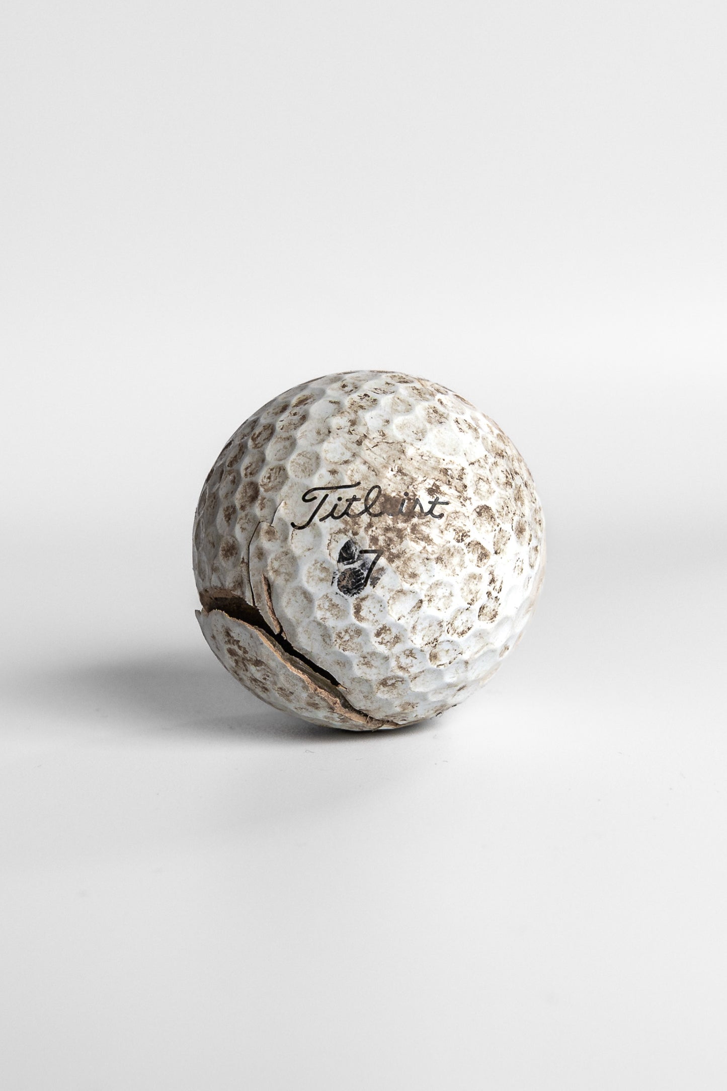 Titleist Pro V1 worn golf ball with scuff marks and dirt white background